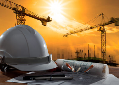 safety helmet and architect pland on wood table with sunset scene and building construction